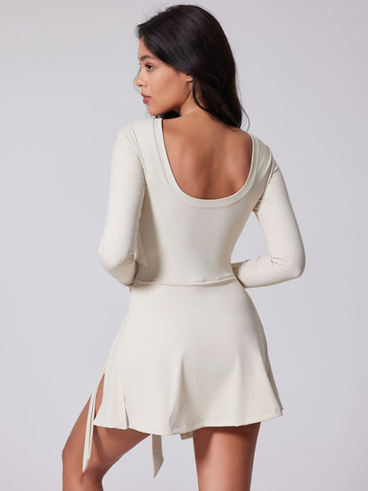 Woman wearing a white dress with long sleeves on a plain background