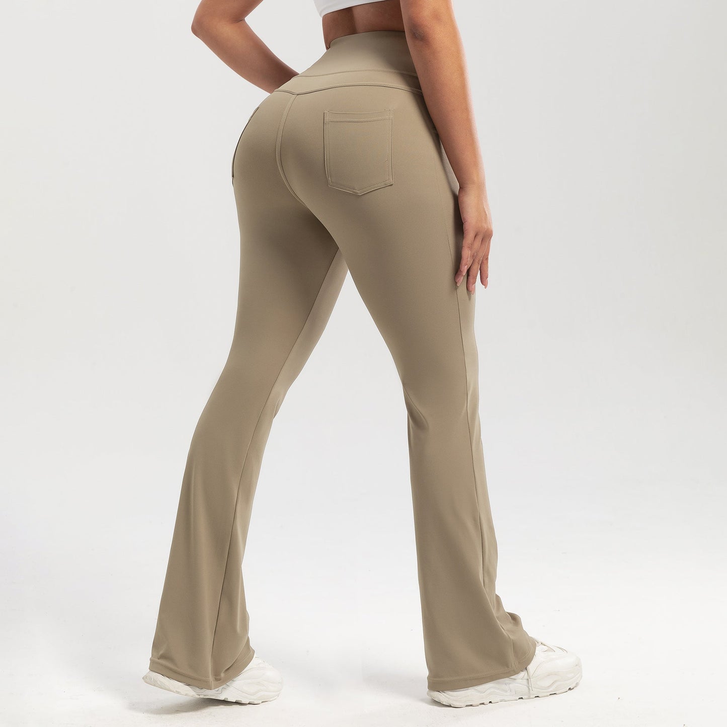 Beige flared pants worn by a person on a white background