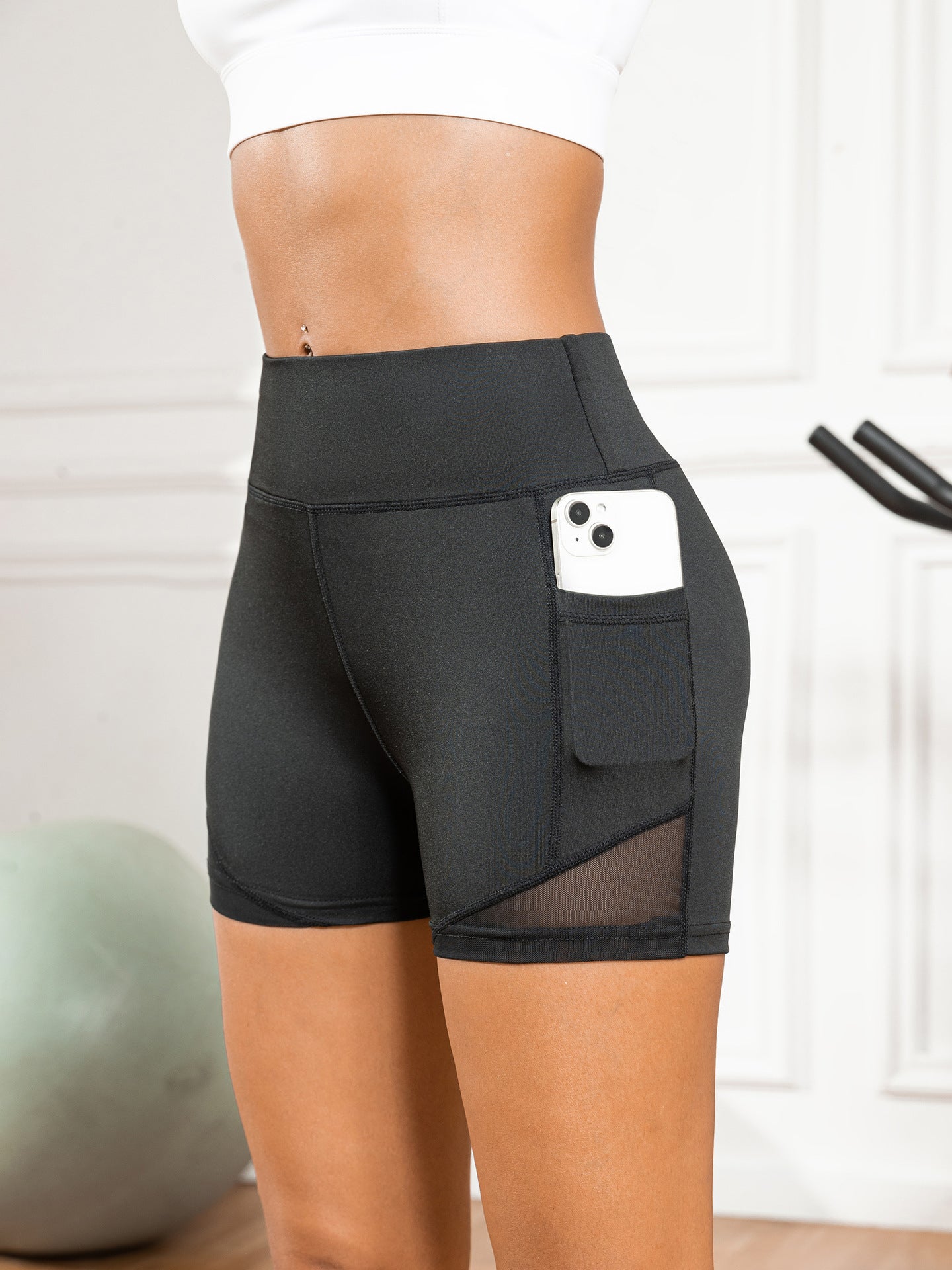 Black athletic shorts with a pocket holding a phone, worn by a person indoors.