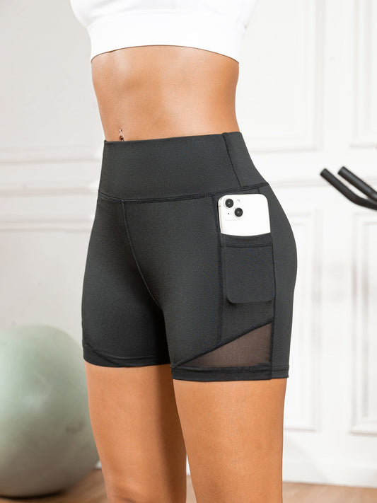 Black athletic shorts with a pocket holding a phone, worn by a person indoors.