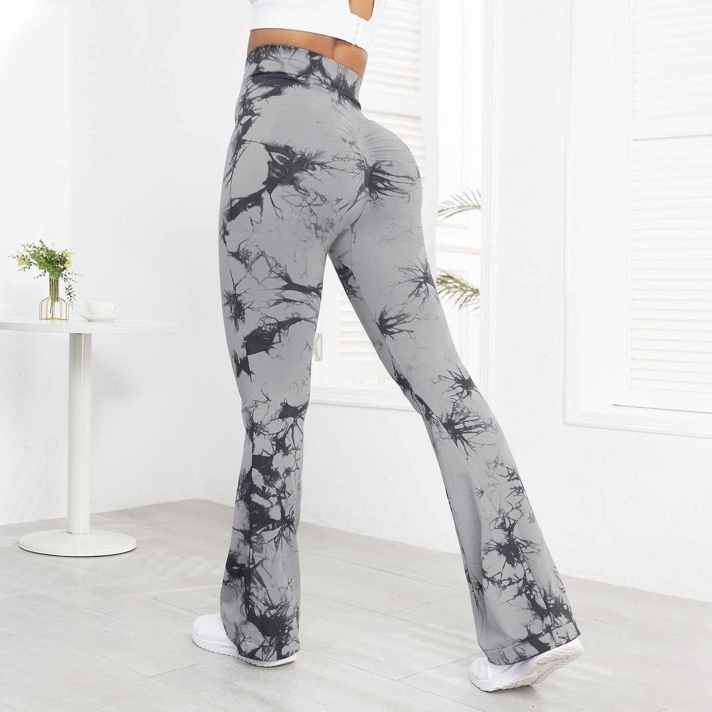 Gray tie-dye pants worn by a person in a minimalistic room.
