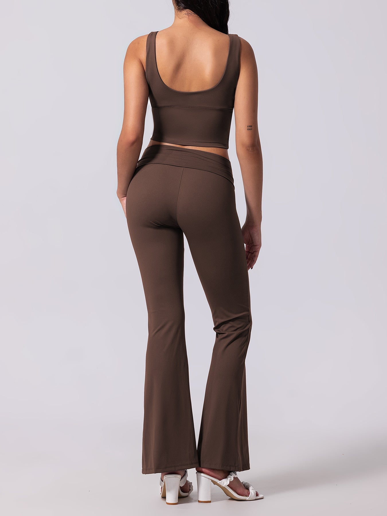 Person wearing a brown outfit with flared pants on a white background