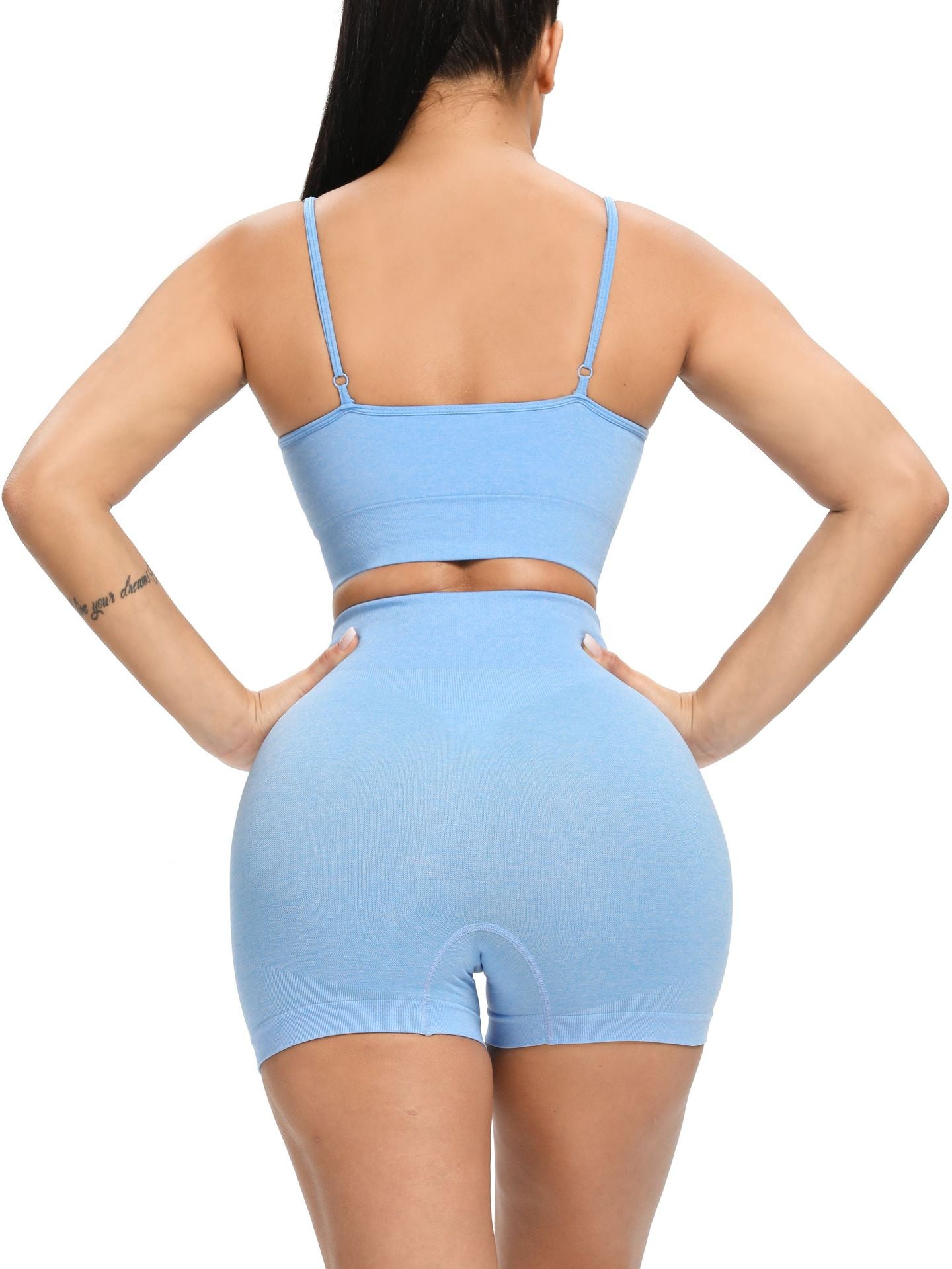 Person wearing a light blue sports bra and high-waisted shorts set on a white background