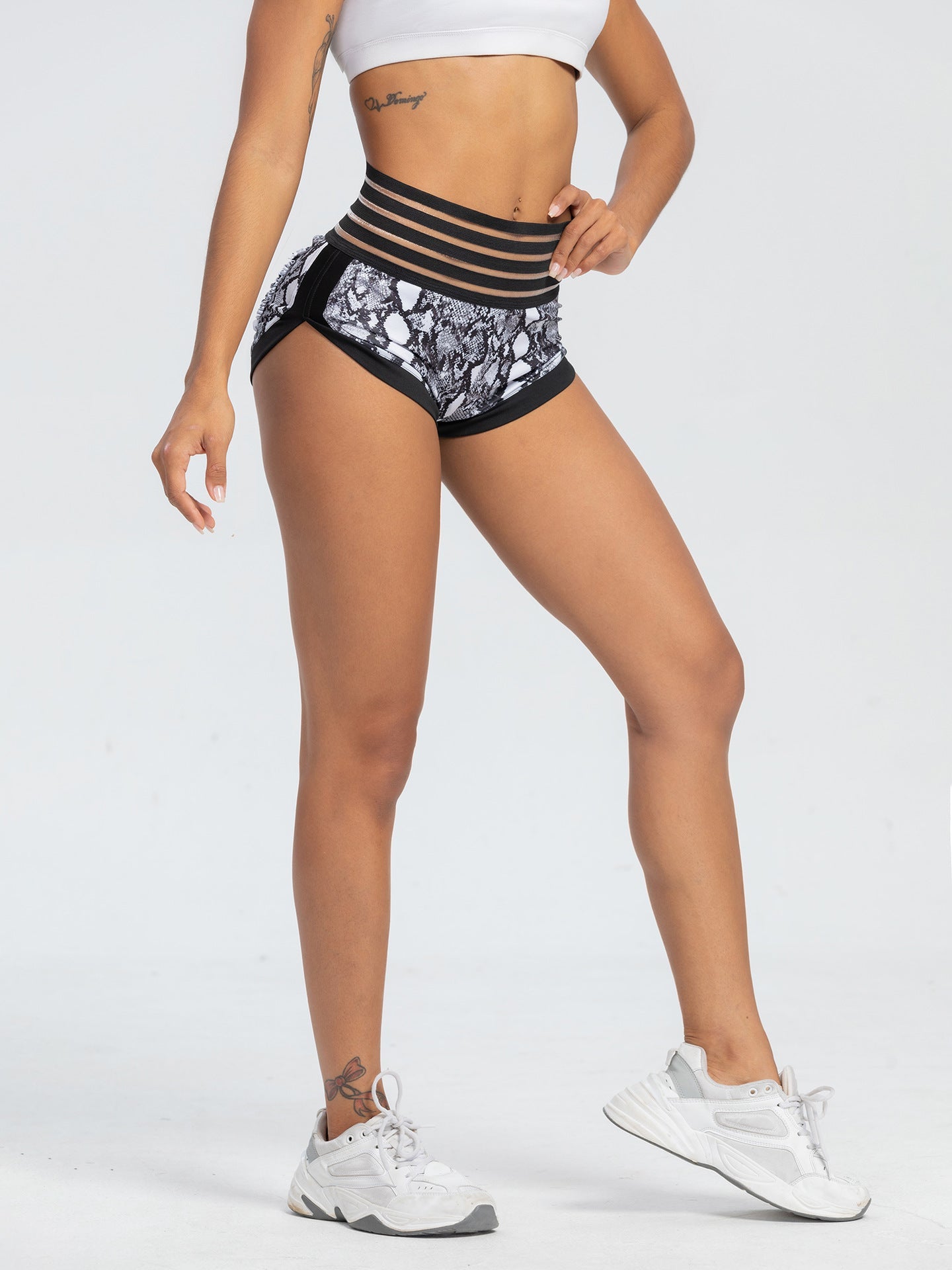 Person wearing black and white patterned shorts on a plain background