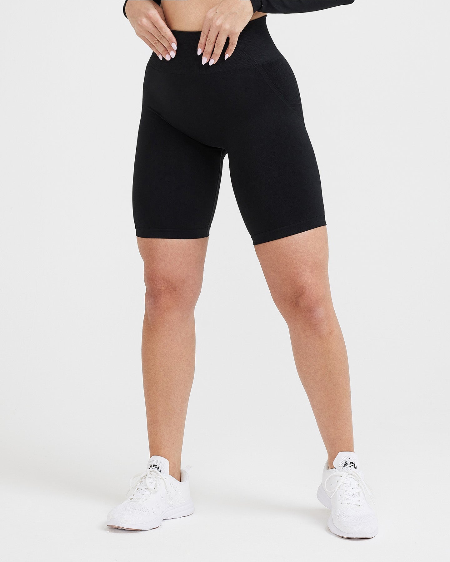 Person wearing black high-waisted shorts on a white background
