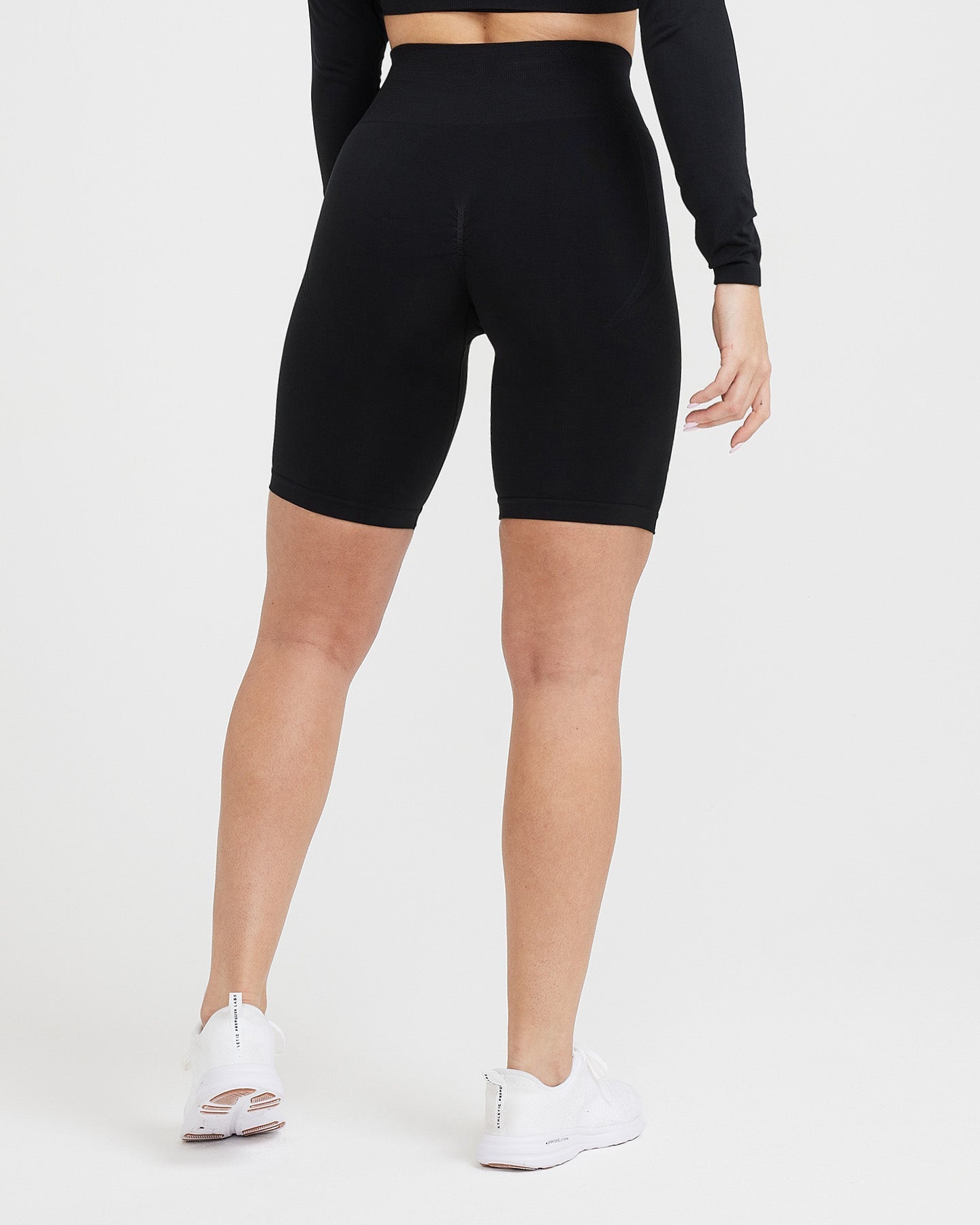 Person wearing black high-waisted bike shorts on a white background