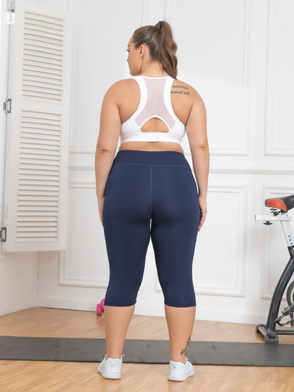 Person wearing navy blue leggings and a white sports bra in a home setting.