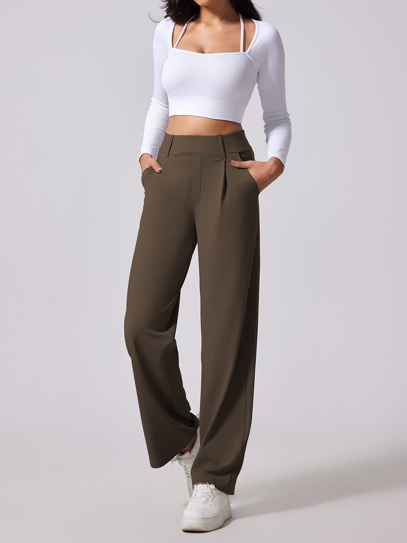 Person wearing brown wide-leg pants and a white top on a light gray background