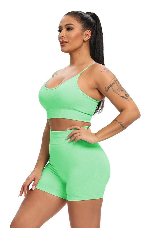 Woman wearing a bright green sports bra and shorts set on a white background