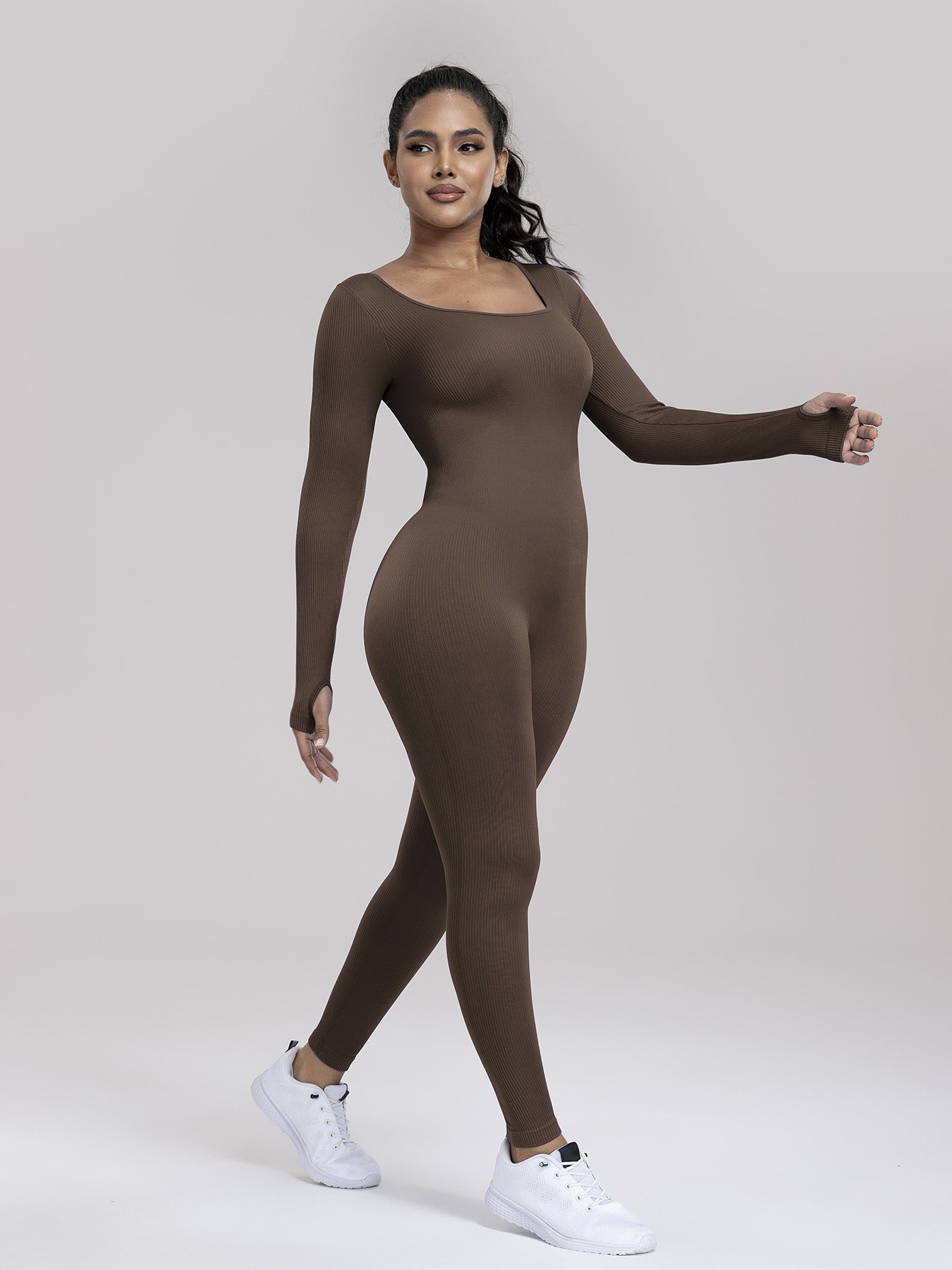 Woman wearing a brown bodysuit on a plain background