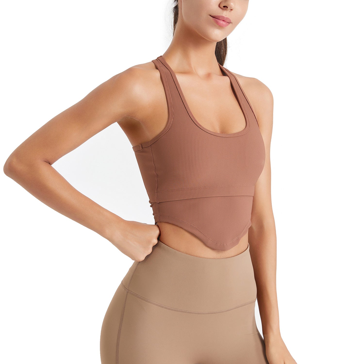 Woman wearing a brown ribbed tank top and leggings on a white background