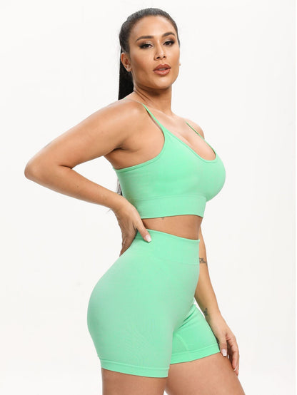 Woman wearing a green sports bra and shorts set on a white background