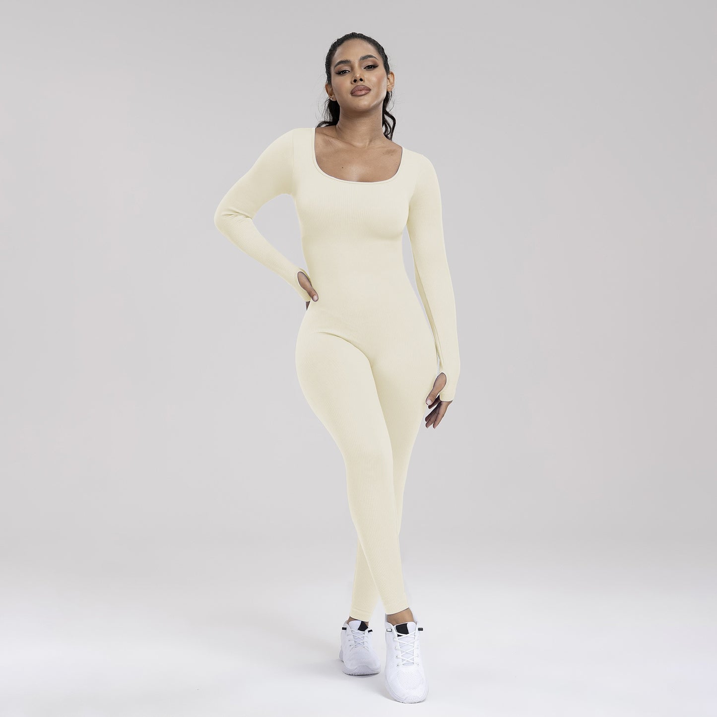 Woman wearing a light yellow long-sleeve top and leggings set on a plain background
