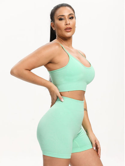 Woman wearing a mint green sports bra and shorts set on a white background