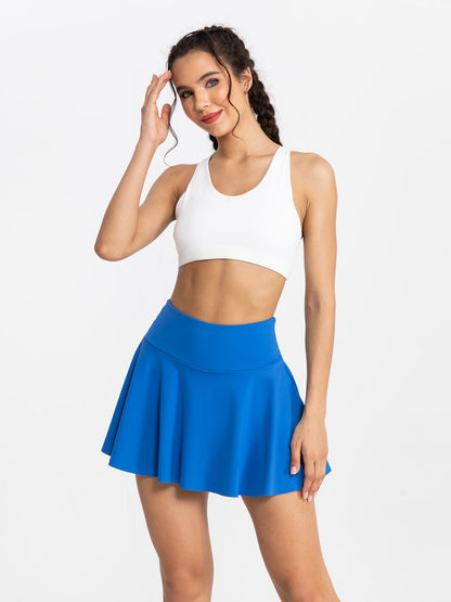 Woman wearing a white crop top and blue skirt on a white background
