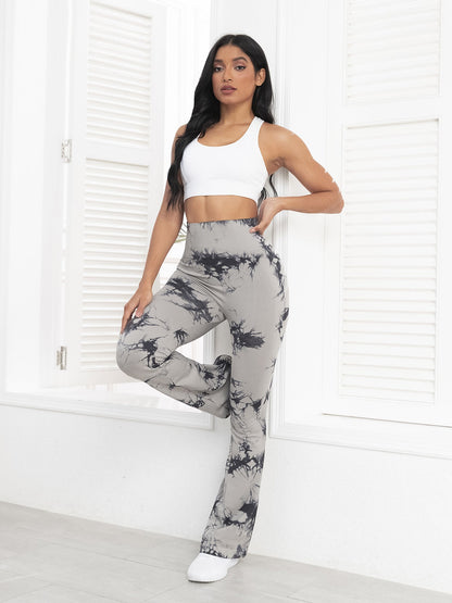 Woman wearing a white crop top and gray tie-dye pants in a minimalistic room.