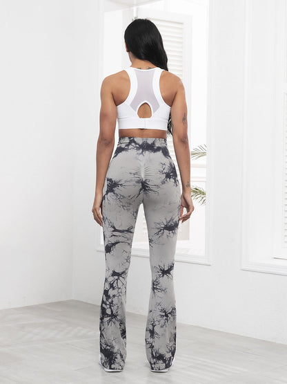 Woman wearing a white sports bra and gray tie-dye leggings in a minimalistic setting.