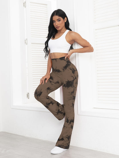 Woman wearing a white top and brown tie-dye pants in a minimalistic setting