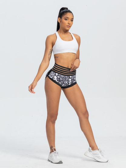Woman wearing a white sports bra and patterned shorts on a white background