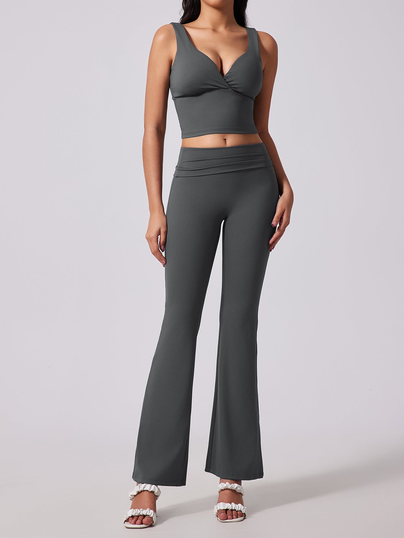 Woman wearing a gray sports bra and leggings set on a light gray background