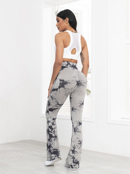 Woman wearing a white sleeveless top and gray tie-dye pants in a minimalistic setting.