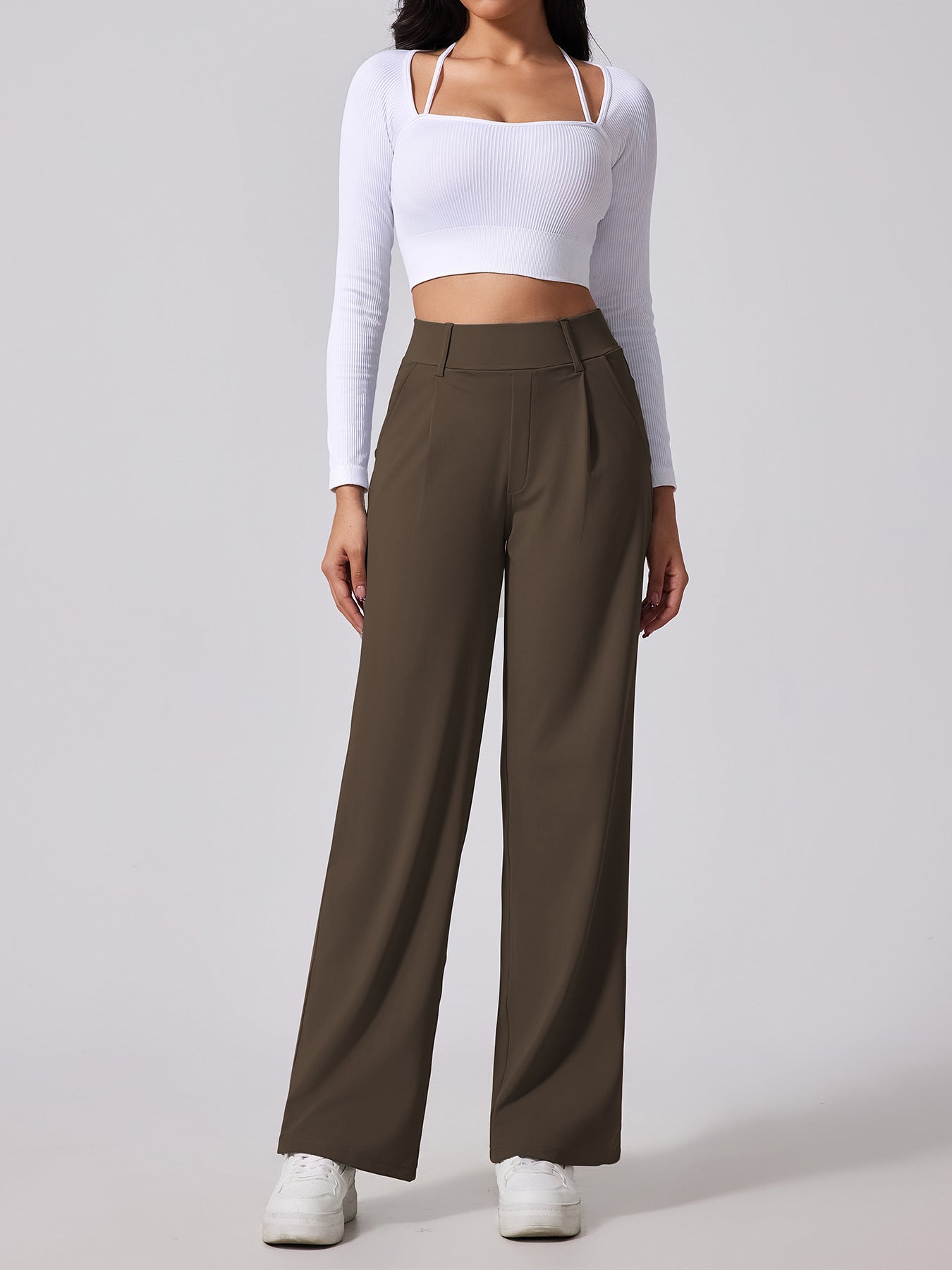 Person wearing a white long-sleeve top and brown wide-leg pants on a light gray background