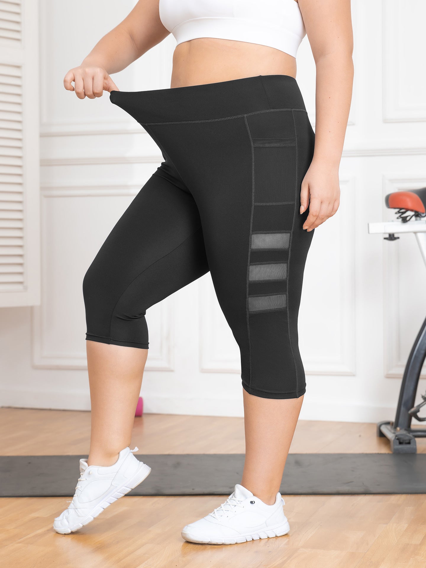 Person wearing black capri leggings with mesh panels in a home setting